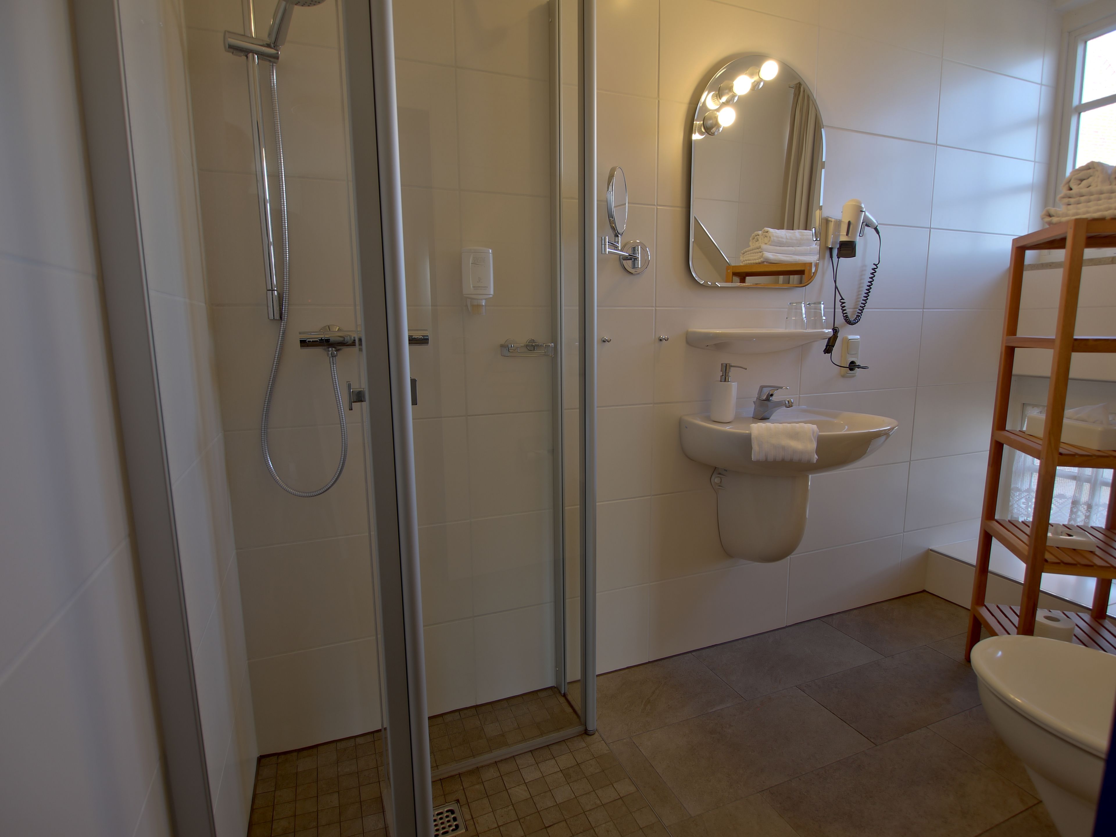 A modern bathroom with a glass shower enclosure, a sink with a mirror, and a toilet.