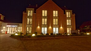 A hotel with a brick facade, large windows, and a well-lit entrance. - Hotel Friesische Wehde (Bockhorn)