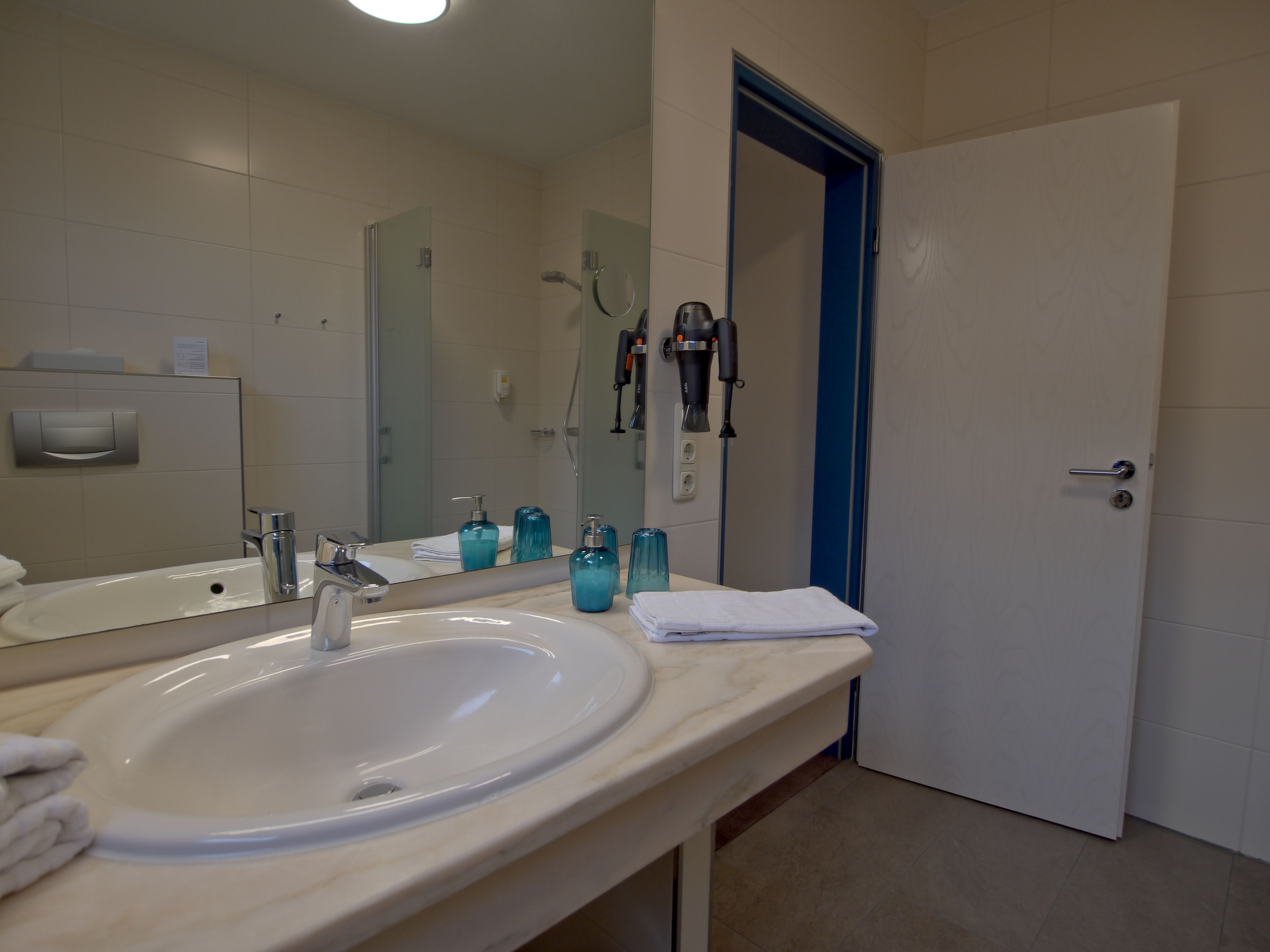 A bathroom with a large sink, a mirror, a towel rack, and a door.
