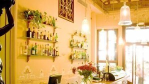 A bar area with a wooden counter, shelves with bottles, and a decorative ceiling. - Hotel La Vila (Sóller)