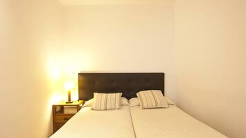 A double bed with a dark headboard, two pillows, and a bedside table with a lamp.