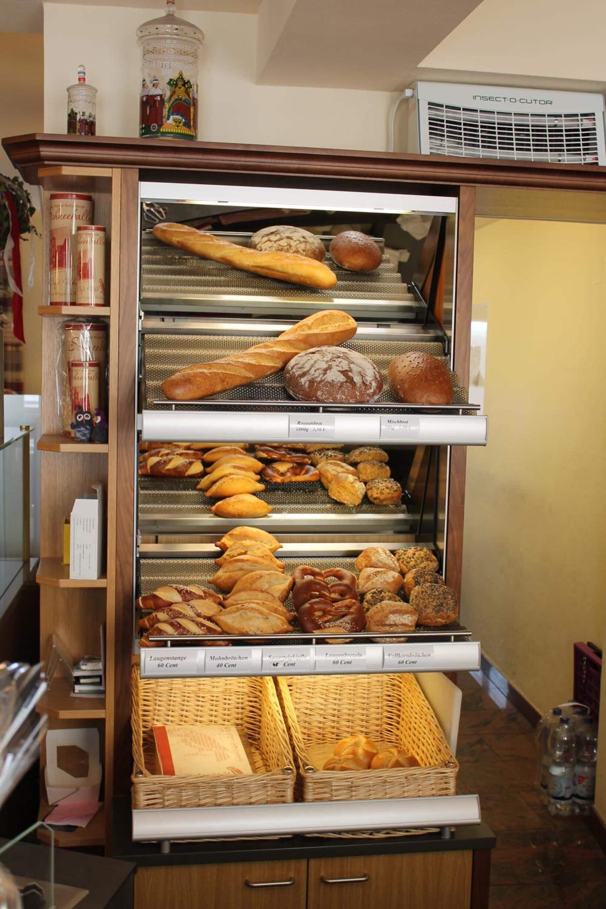 Vitrina de panadería con panes y pasteles varios, incluyendo etiquetas que identifican los tipos de pan.