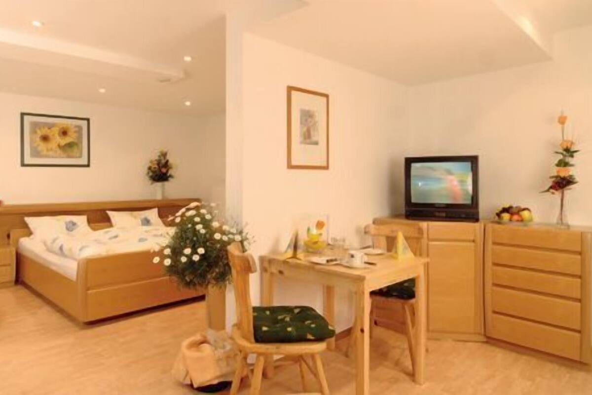 Una habitación de hotel pequeña con cama, escritorio, televisor y sofá.