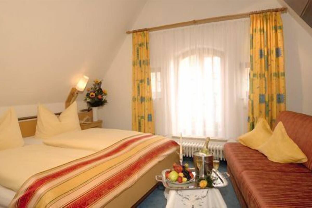 Una habitación de hotel con cama, sofá, una mesa con fruta y un radiador.