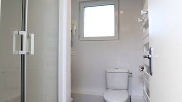 Ein modernes Badezimmer mit Duschkabine aus Glas, Toilette und Fenster für natürliches Licht.