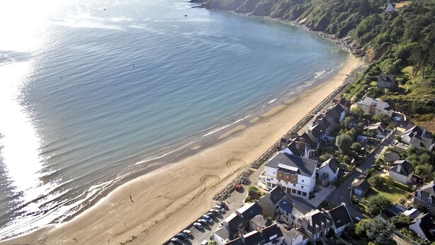 An aerial view of a coastal town with a sandy beach, houses, and a cliff. - Hôtel Miléade de la Plage - Binic (Binic-Etables-sur-Mer)