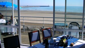 A restaurant with a view of the beach, outdoor seating, and a table set for dining. - Hôtel Miléade de la Plage - Binic (Binic-Etables-sur-Mer)