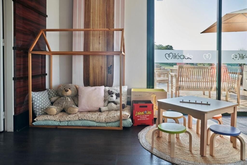Un área de juegos infantiles con una casita de madera, una mesa y sillas.