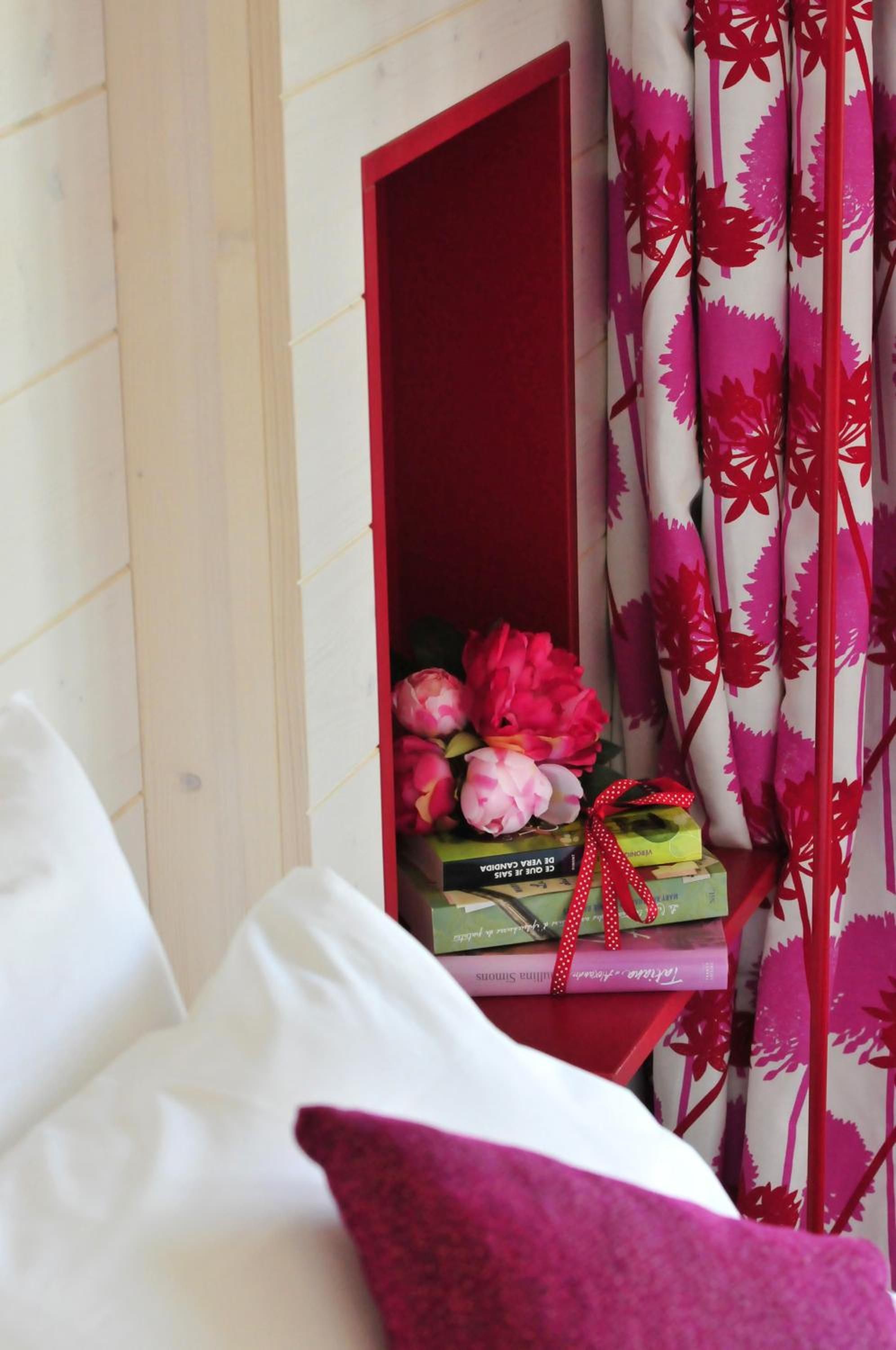 Ein Schlafzimmer mit einem Holzkopfteil, einem roten Nachttisch und einem pinken Kissen.