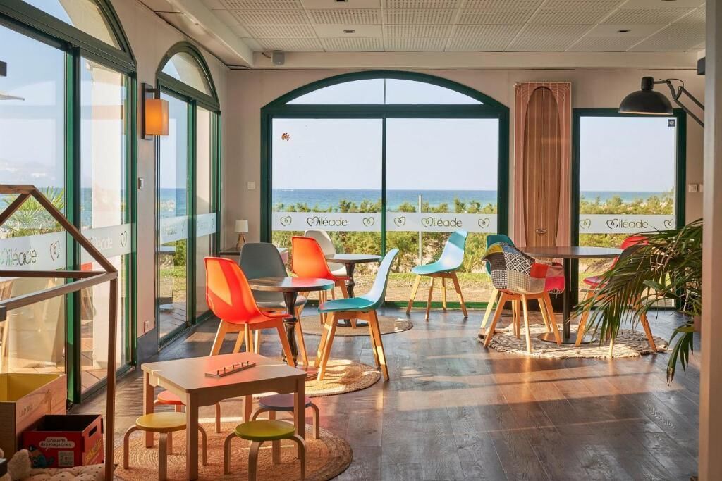 Un comedor con vista al océano, con sillas y mesas de colores.