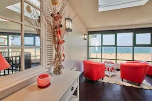 A room with a view of the beach, a vase with dried plants, a red chair, and a small table. - La Frégate - Bidart - Hôtel by Miléade (Bidart)
