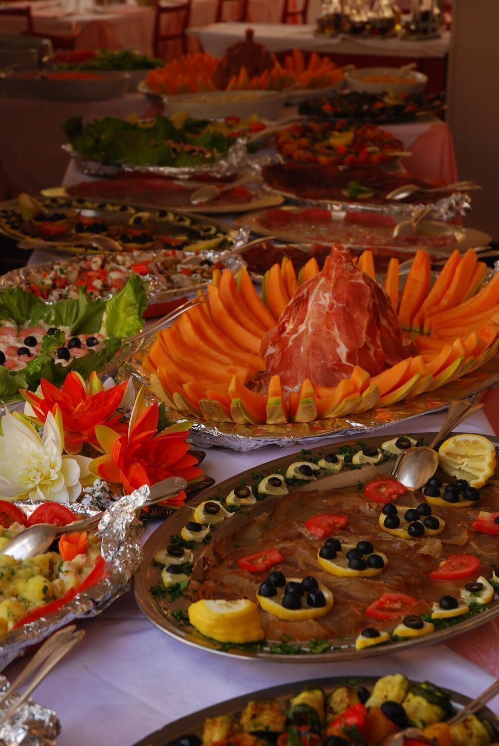 Un bufé con diversos platos, incluyendo carnes, verduras y ensaladas.
