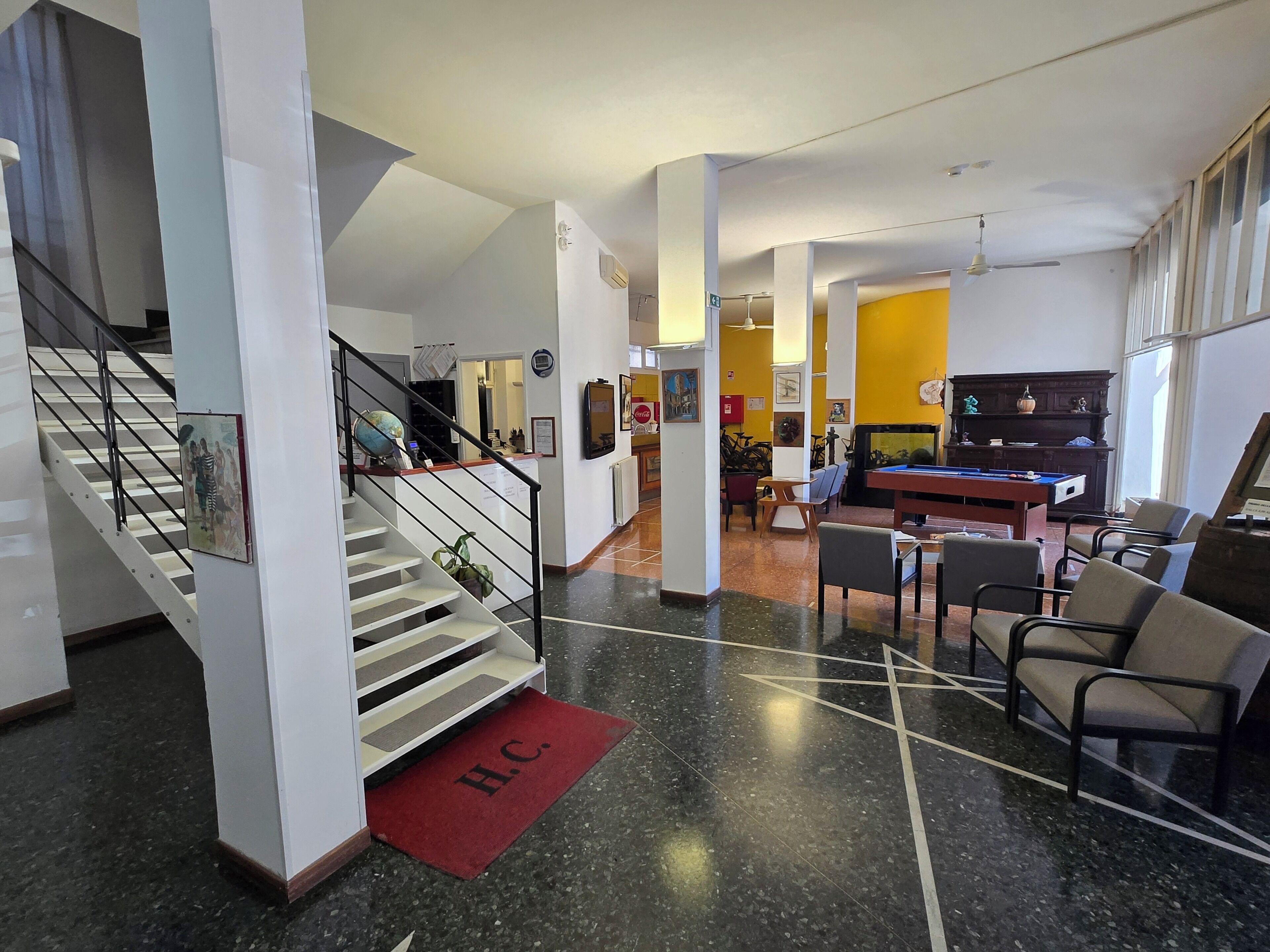 A hotel lobby with a staircase, a pool table, and a reception desk.