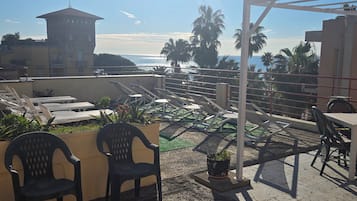 Una terraza en la azotea con sillones de descanso, una mesa y vistas al mar.