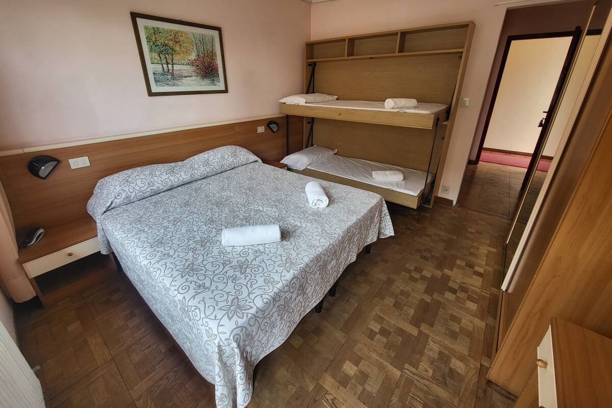 A room with a bed, a desk, a chair, a shelf, and a painting on the wall.