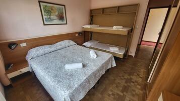 Una habitación con cama, escritorio, silla, estante y un cuadro en la pared.
