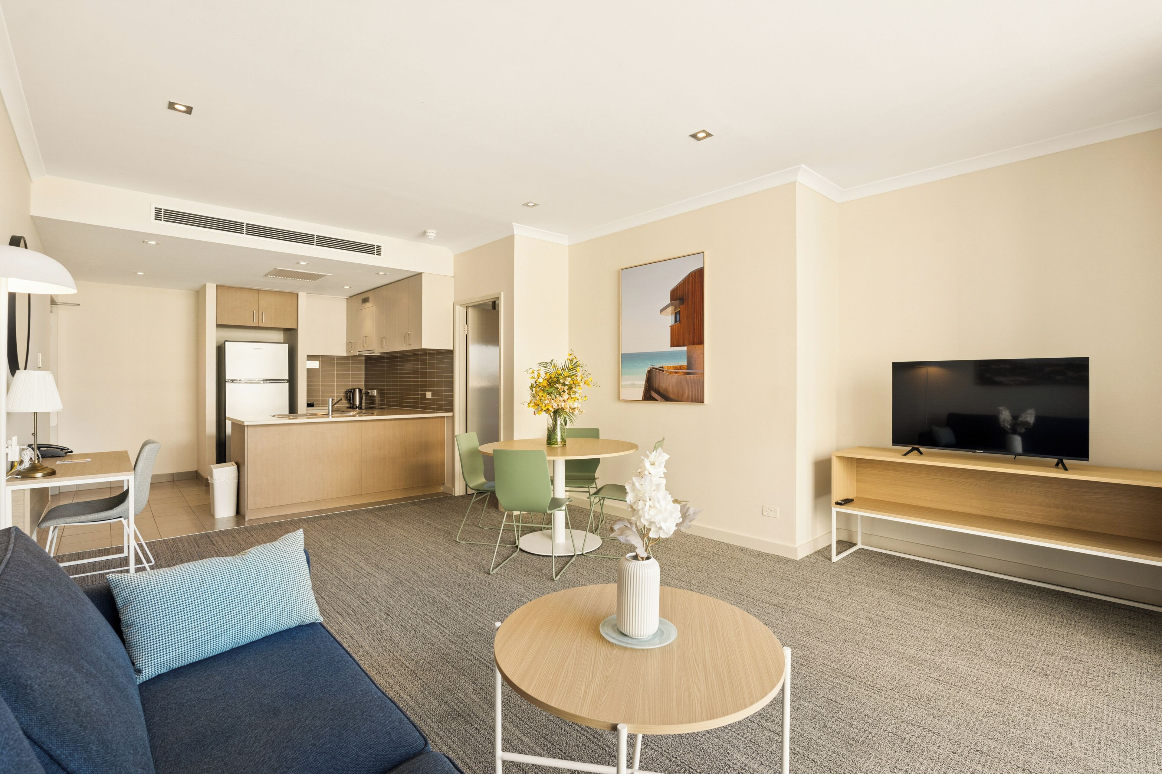 Una habitación de hotel moderna con sala de estar, kitchenette y televisión.