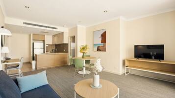 Una habitación de hotel moderna con sala de estar, kitchenette y televisión.
