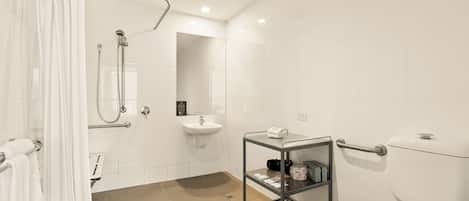 A modern bathroom with a shower, toilet, sink, and a glass shelf with toiletries.
