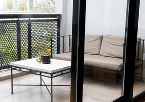 A balcony with a white table, a beige sofa, and a potted plant. - Hotel Palermitano by DOT Boutique (Buenos Aires)