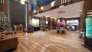 A spacious lobby with a Christmas tree, leather armchairs, and a reception desk.