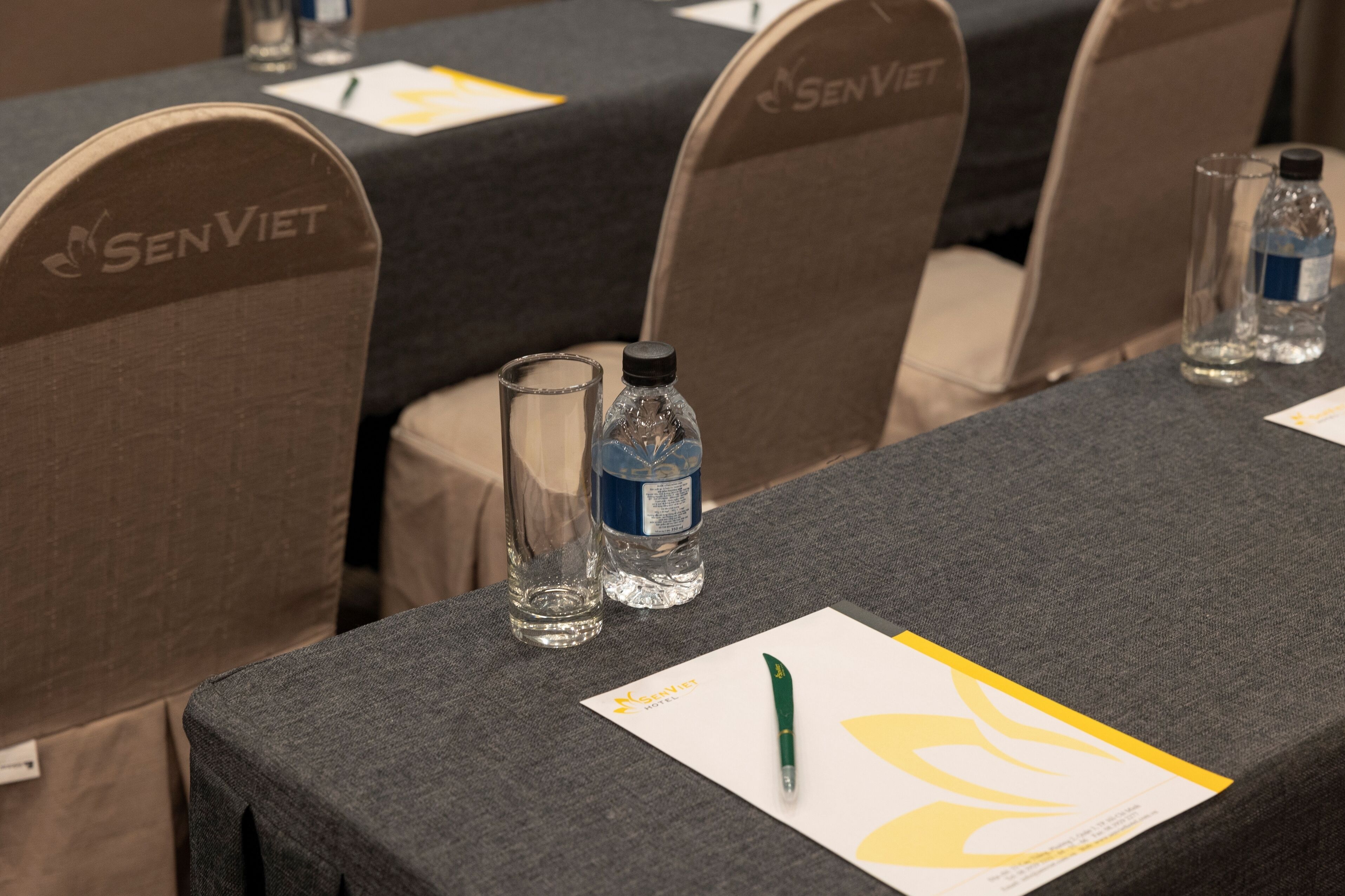 A conference room with tables, chairs, water bottles, and name cards.