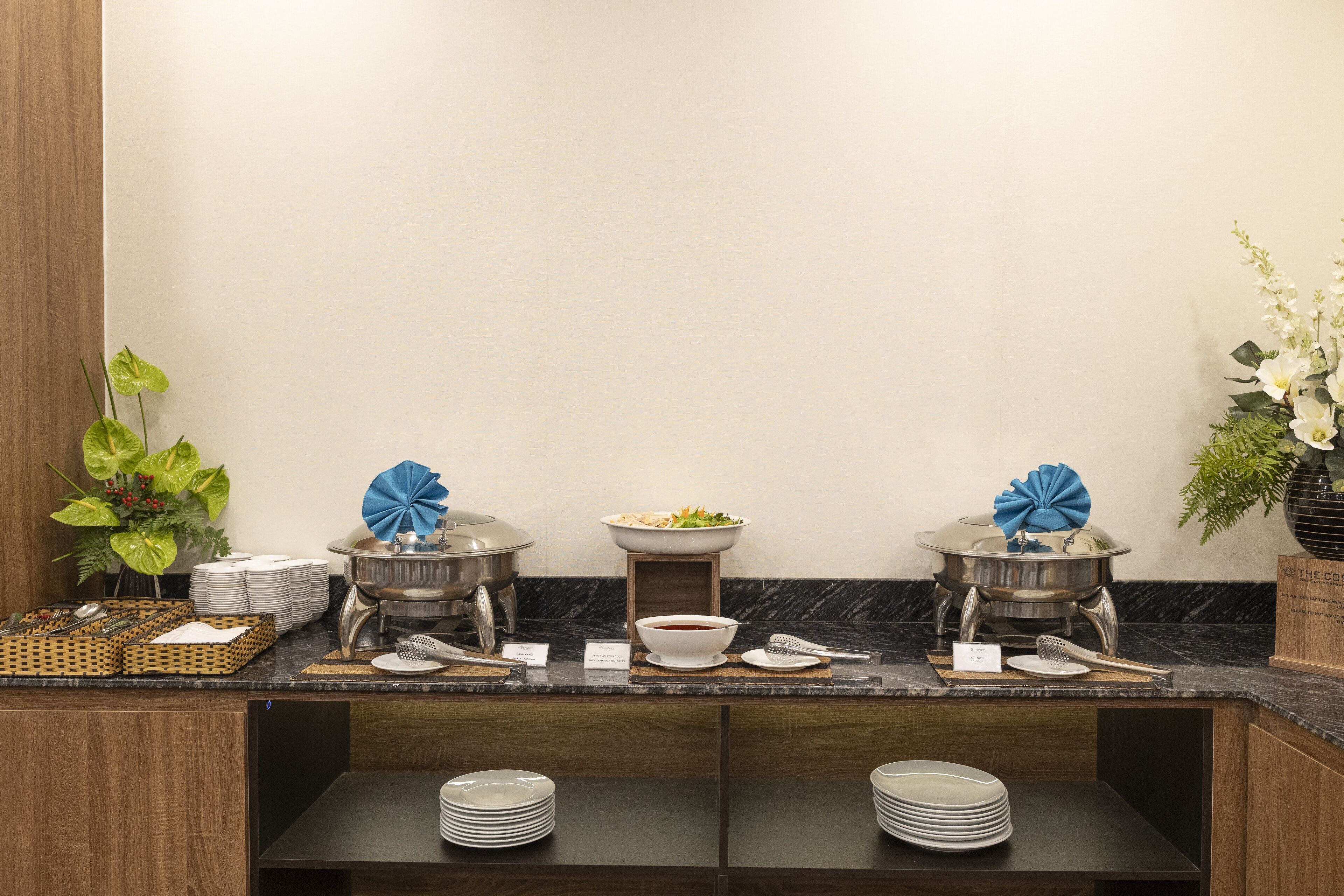 A buffet setup with multiple serving stations, plates, bowls, and utensils.