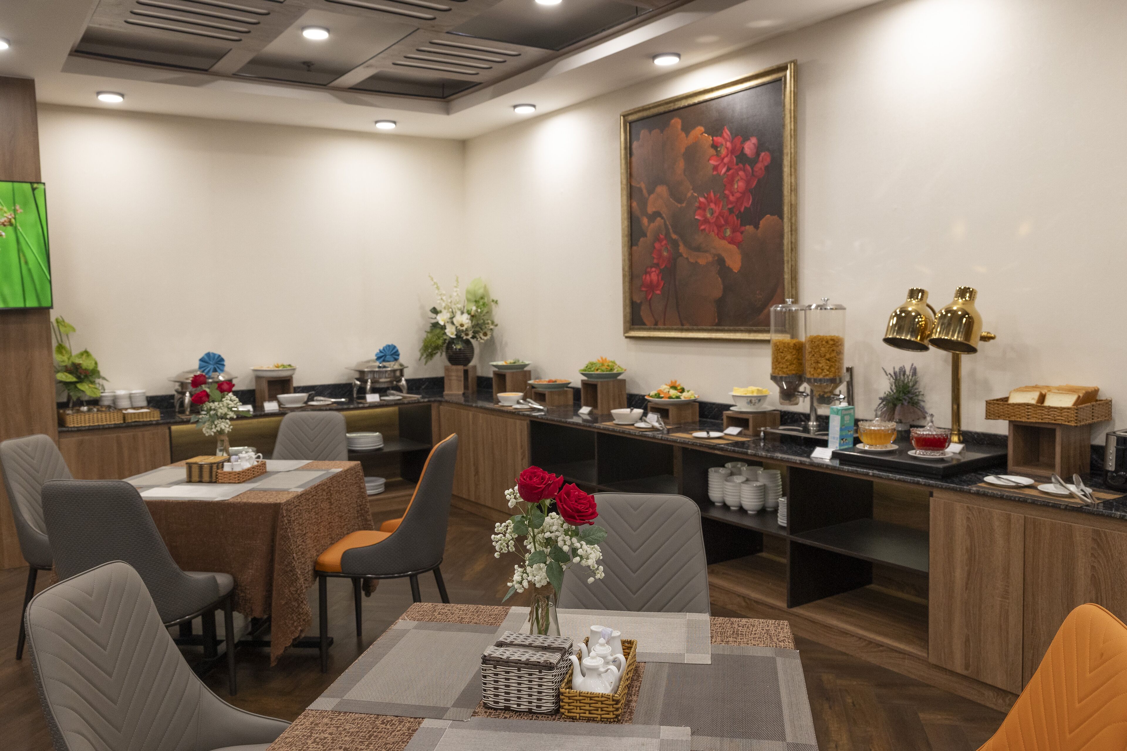 A hotel lobby with a reception desk, seating area, and a large floral painting on the wall.