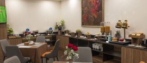 A hotel lobby with a reception desk, seating area, and a large floral painting on the wall.