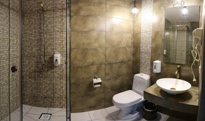 A bathroom with a glass-enclosed shower, a toilet, a sink, and a mirror.