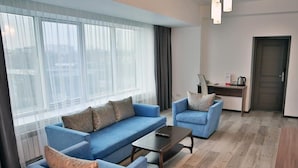 A modern living room with a blue sofa set, a coffee table, and a desk with a kettle. - Astra (Almaty)