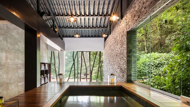A modern indoor pool with a view of lush greenery, a wooden ceiling, and a glass wall. - El MaPi Hotel by Inkaterra (Machu Picchu)