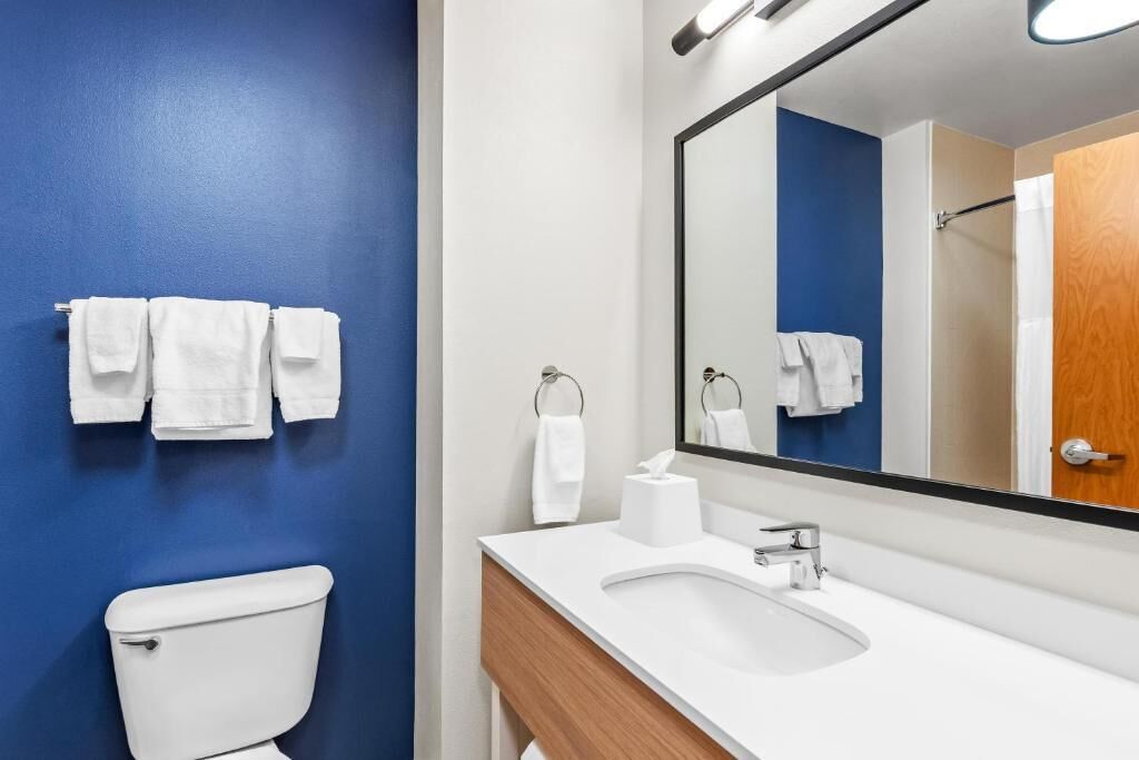 A bathroom with a toilet, sink, and mirror.