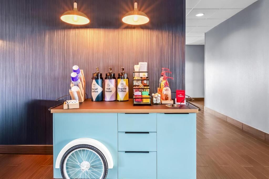 Un espace dédié au café, avec une variété de boissons et d’en-cas, un comptoir décoré avec un motif de roue de vélo et deux lampes suspendues.