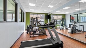 Un gimnasio con cintas de correr, elípticas y equipo de pesas.