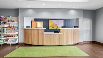 En hotellreception med en grön matta, träpanel och en stor, abstrakt målning.