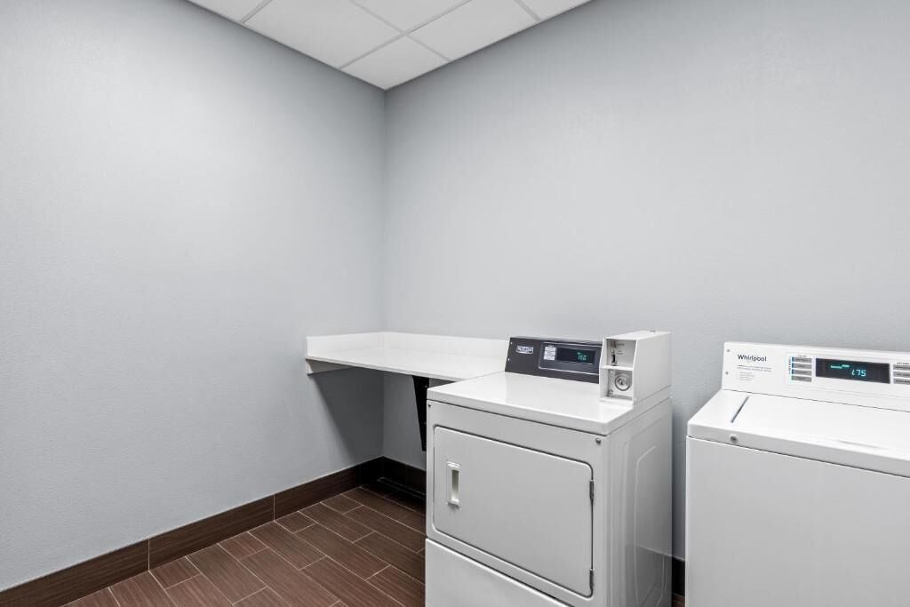 Un cuarto de lavado con una pared blanca, una repisa y dos lavadoras Whirlpool blancas.