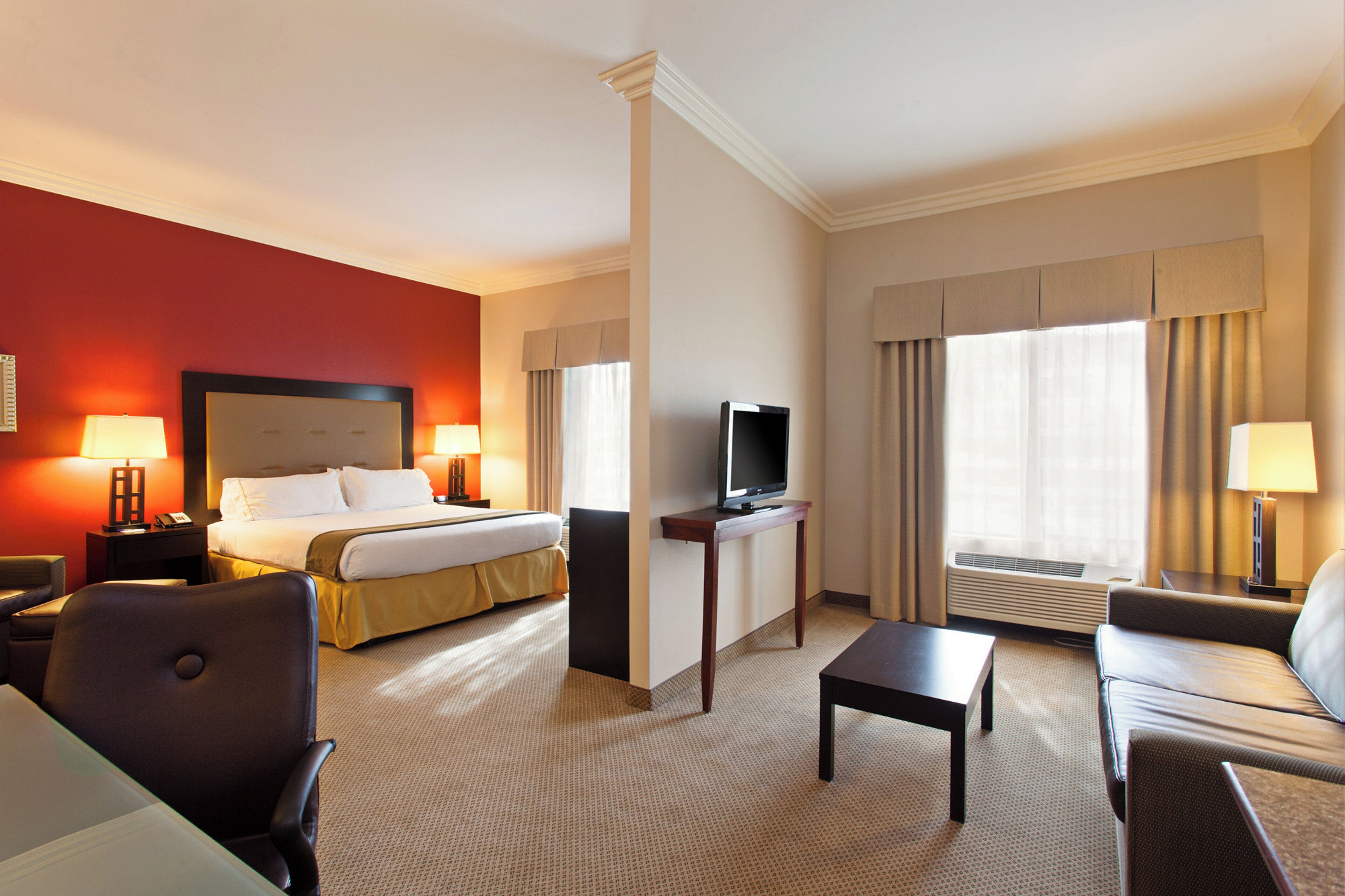 Habitación de hotel con una cama, televisión, escritorio y dos sillas.