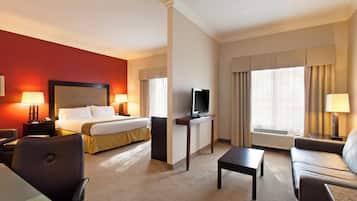 Habitación de hotel con una cama, televisión, escritorio y dos sillas.