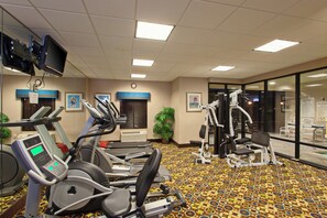 Een hotelgymzaal met loopbanden, hometrainers en krachtapparaten.