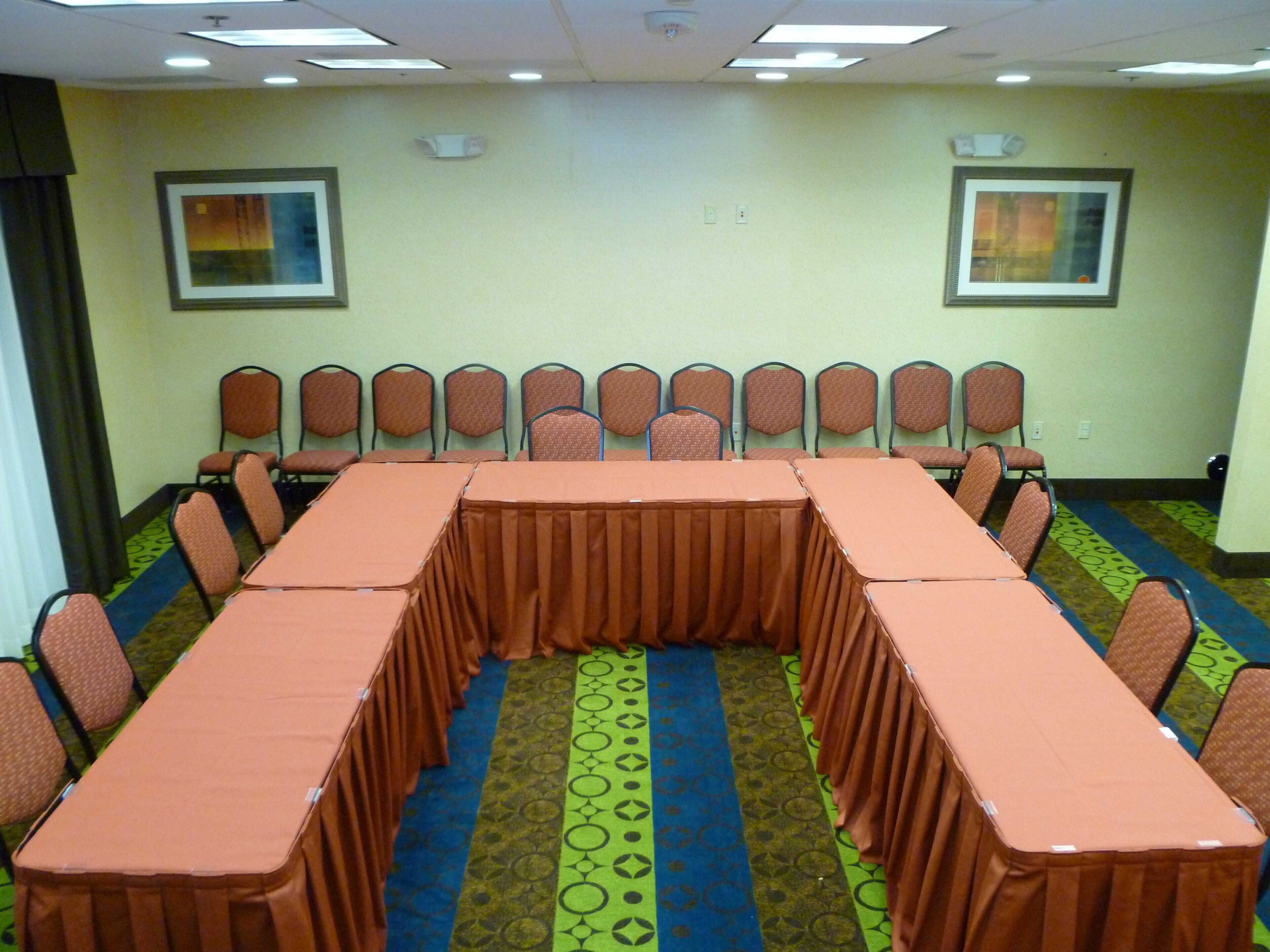 Un salón de conferencias con una larga mesa, sillas y alfombra estampada.