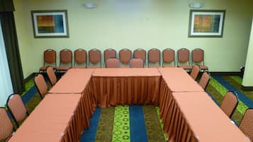 Un salón de conferencias con una larga mesa, sillas y alfombra estampada.