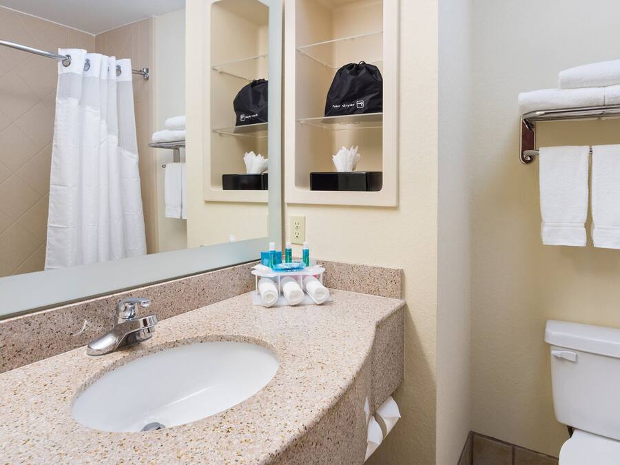 A bathroom with a sink, mirror, towel rack, and toilet.