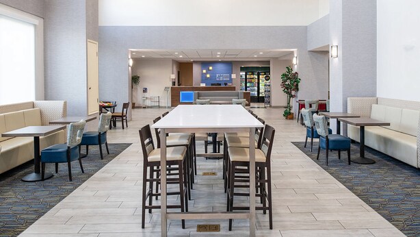 Un amplio vestíbulo de hotel con zona de comedor central, espacios de estar y un mostrador de recepción.