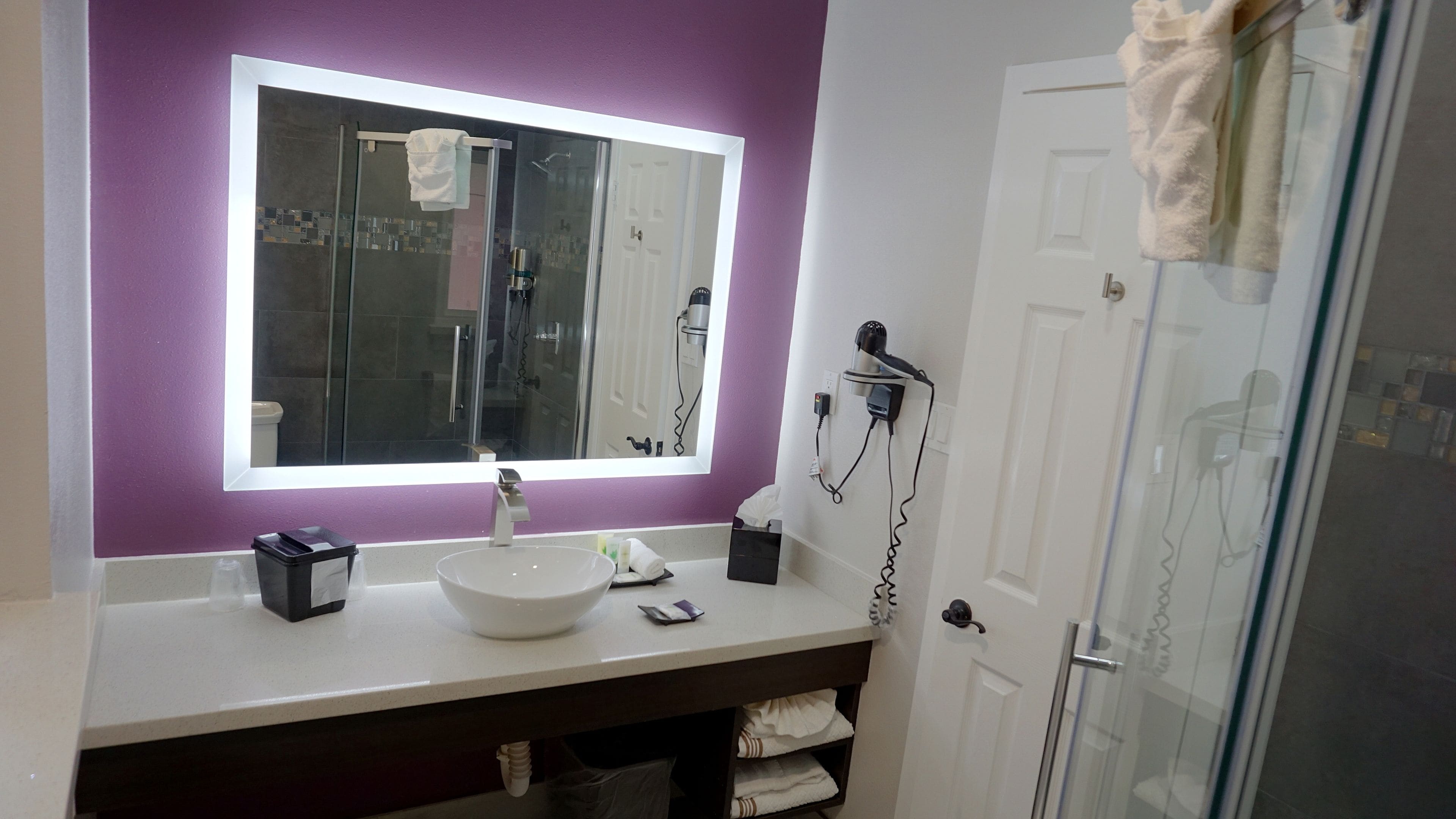 A bathroom with a white sink, a large mirror, and a glass shower enclosure.