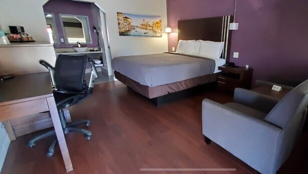 Una habitación de hotel con una cama, un escritorio, una silla y una mesita.