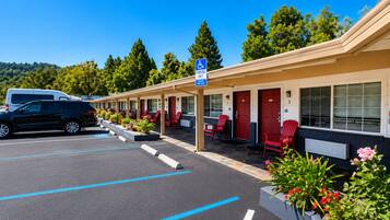 Ein Motel mit Parkplatz, roten Stühlen und einem blauen Parkplatzschild für Rollstuhlfahrer.
