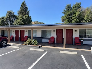 A motel with numbered rooms, red doors, and a parking lot. - Muir Lodge Motel (Martinez)
