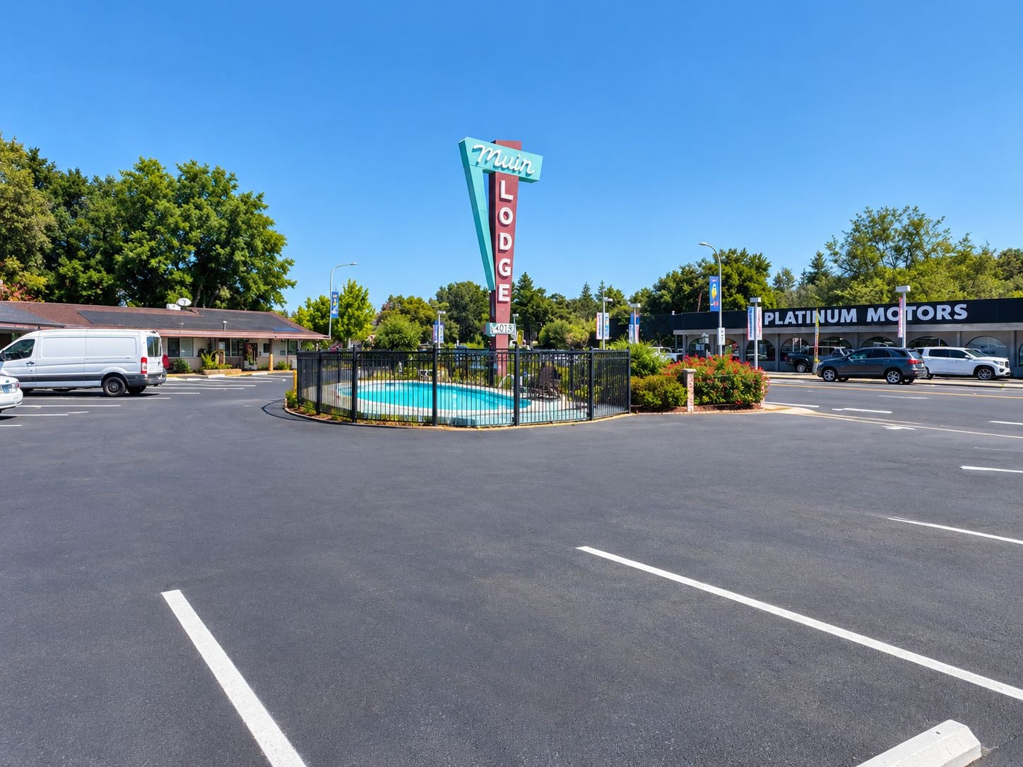 A motel sign, a swimming pool, and a Platinum Motors dealership.