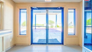 A hotel entrance with a double door, a blue mat, and an exit sign.